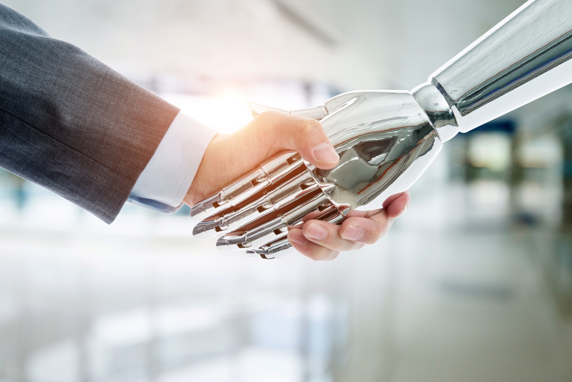 Businessman and robot shaking hands on modern office background